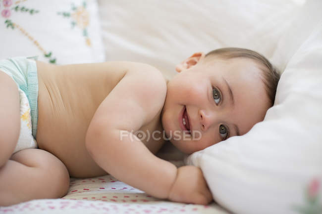 Bambino sdraiato sul letto e guardando la fotocamera — Foto stock