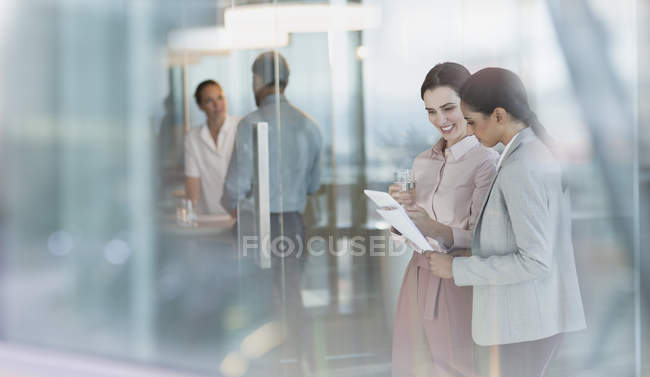 Mulheres de negócios conversando, revisando papelada no escritório — Fotografia de Stock