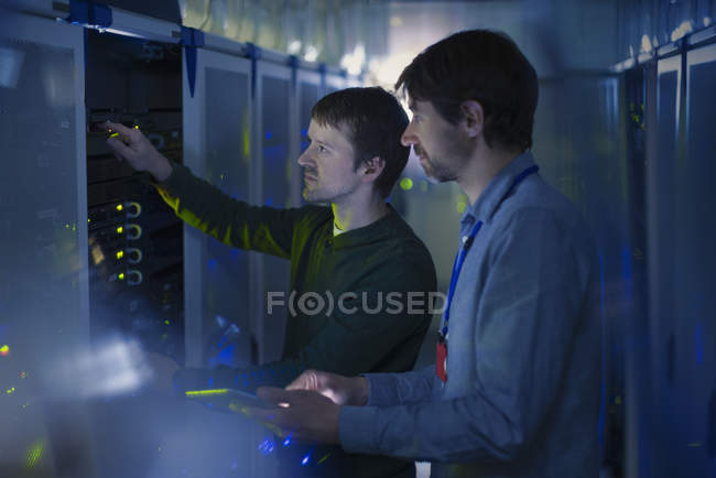 Técnicos de sala de servidores trabajando en panel - foto de stock