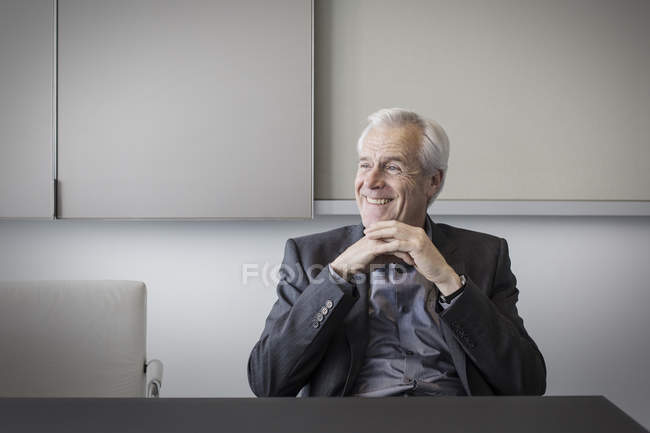 Усміхнений старший бізнесмен, дивлячись на сучасний офіс — стокове фото