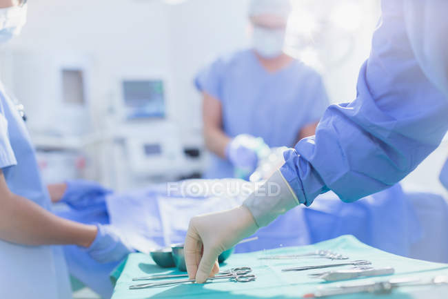 Хірург у гумові рукавички досягнення для хірургічного ножиці на лоток в операційний зал — стокове фото