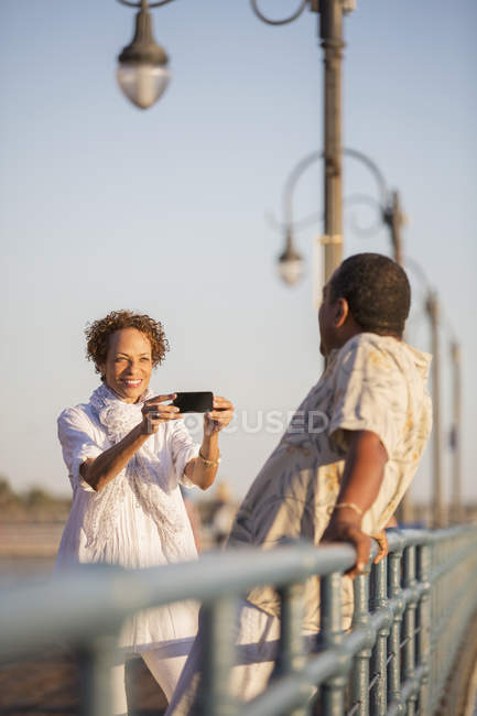 Donna che fotografa l'uomo sul molo — Foto stock