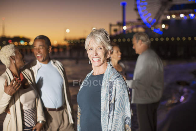 Porträt einer begeisterten Seniorin mit Freunden am nächtlichen Strand — Stockfoto