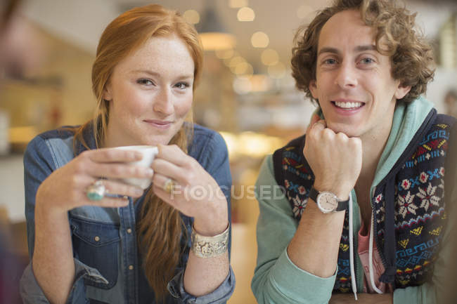 Feliz joven pareja sonriendo juntos en la cafetería - foto de stock