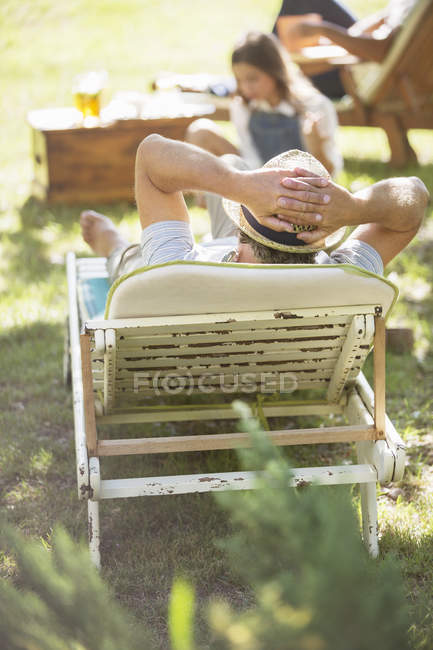 Rückansicht eines älteren Mannes, der es sich auf einem Liegestuhl gemütlich macht — Stockfoto