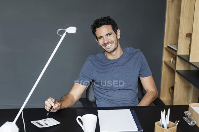 Портрет улыбающегося человека за столом в домашнем офисе — стоковое фото