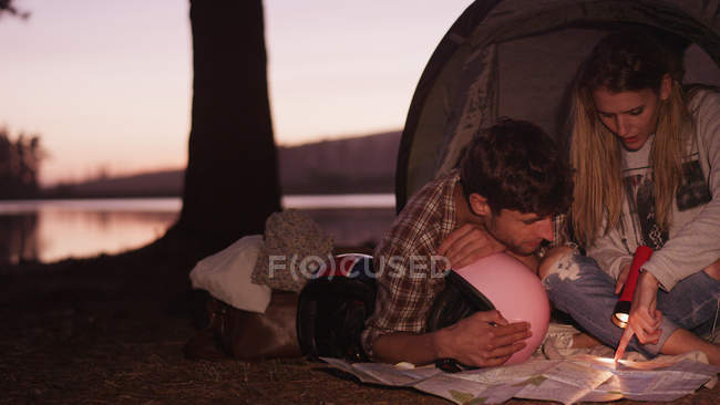 Young couple looking at maps in camping tent — Stock Photo