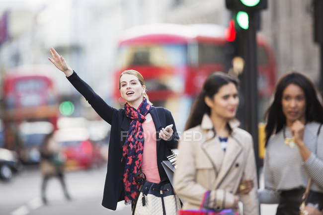 Woman signaling for taxi on city street — Stock Photo