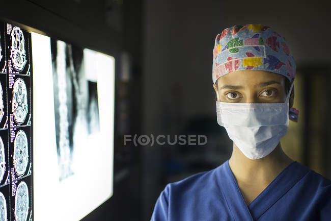 Портрет молодого жіночий лікаря стоїть біля екрану з зображенням МРТ — стокове фото