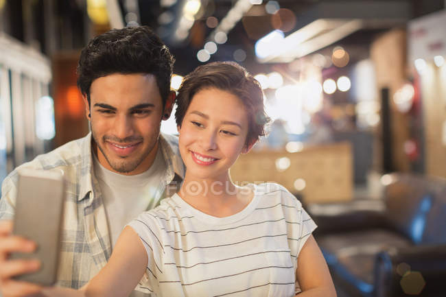 Multicultura giovane coppia prendendo selfie in caffè — Foto stock