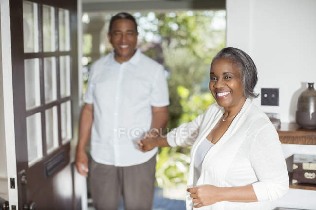 Retrato de una sonriente pareja de ancianos tomados de la mano en la puerta - foto de stock