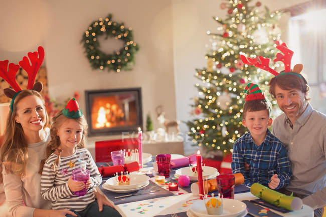 Ritratto sorridente giovane famiglia che indossa corna di renna costume a tavola a Natale — Foto stock
