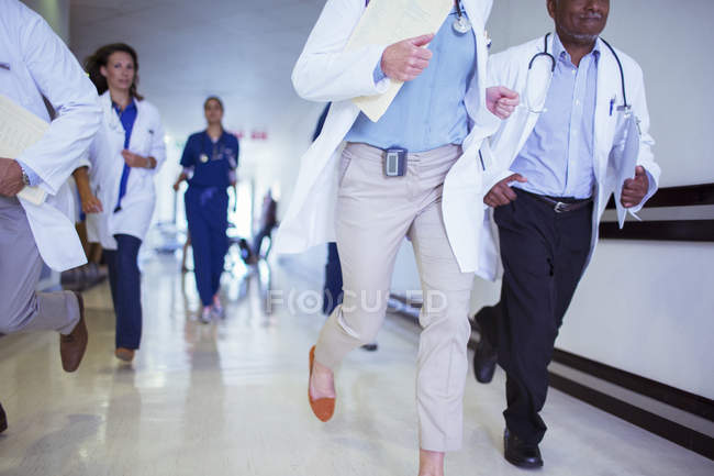 Médicos y enfermeras corriendo en el pasillo del hospital - foto de stock