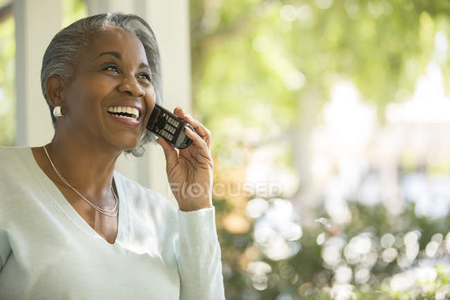 Счастливая пожилая женщина разговаривает по телефону на открытом воздухе — стоковое фото