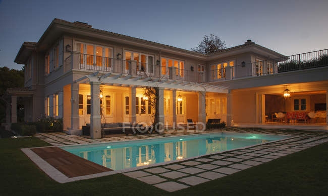 Illuminated luxury house with swimming pool at night — Stock Photo