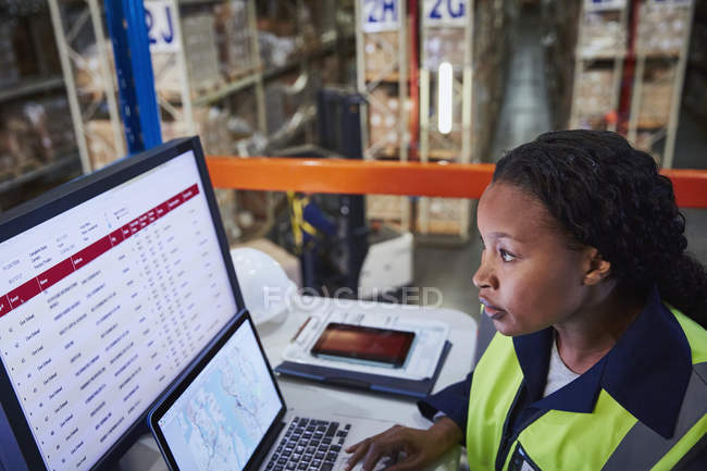 Gerente feminina focada usando laptop e computador em armazém de distribuição — Fotografia de Stock