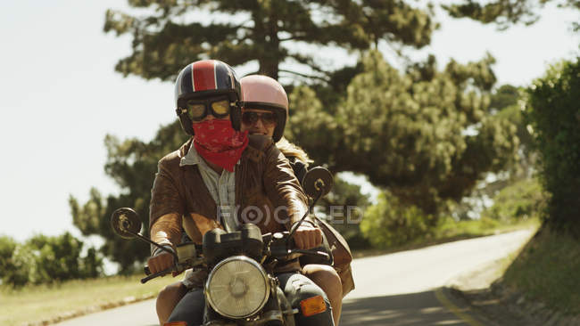 Pareja joven montando motocicleta en camino soleado - foto de stock