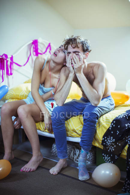 Hungover couple sitting on bed morning after party — Stock Photo