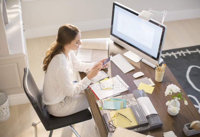 Interior designer texting on cell phone at desk in home office — Stock Photo