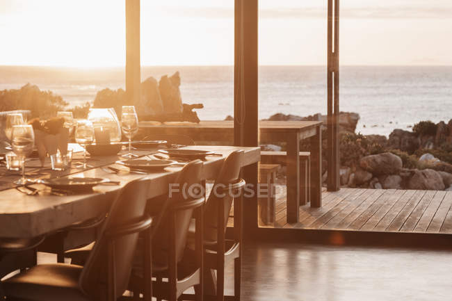 Maison ensoleillée vitrine salle à manger donnant sur l'océan au coucher du soleil — Photo de stock