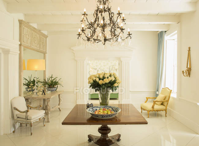 Chandelier over rose bouquet on table in luxury foyer — Stock Photo