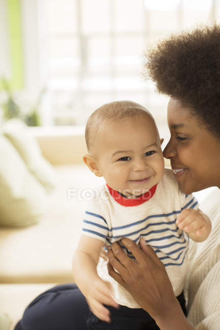 Mother holding baby boy on sofa at home — Stock Photo