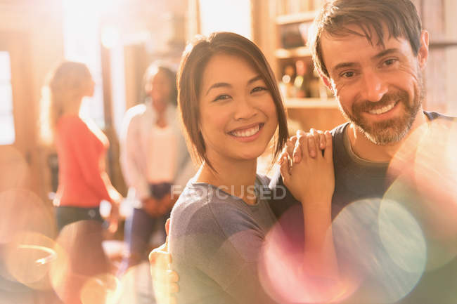 Retrato de pareja multirracial sonriente abrazándose en la cafetería - foto de stock