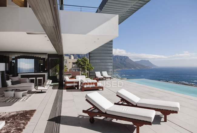 Terrasse moderne et piscine à débordement donnant sur l'océan — Photo de stock
