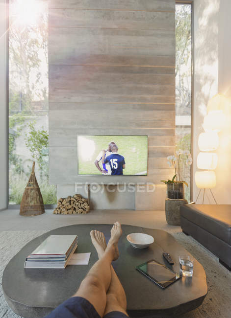 Личная перспектива человека смотреть футбол по телевизору в гостиной — стоковое фото