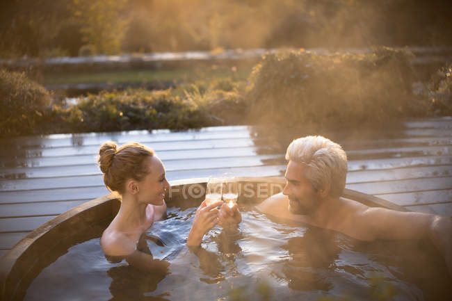 Couple toasting champagne verres trempage dans le bain à remous sur patio d'automne — Photo de stock