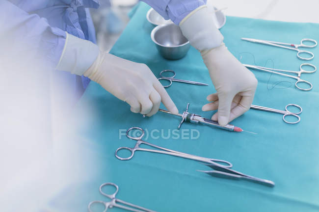 Surgeon in rubber gloves preparing surgical instruments on tray — Stock Photo