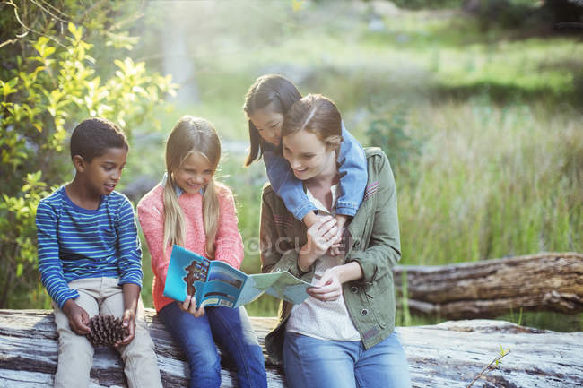 Students and teacher reading map in forest — Stock Photo