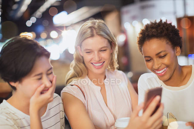 Сміються молоді друзі з мобільним телефоном в кафе — стокове фото
