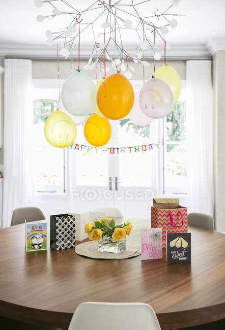 Balões de rosto sorridente e sinal de feliz aniversário pendurado sobre a mesa com cartões — Fotografia de Stock