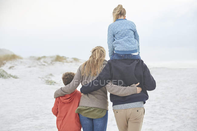 Familia cariñosa caminando en la playa de invierno - foto de stock