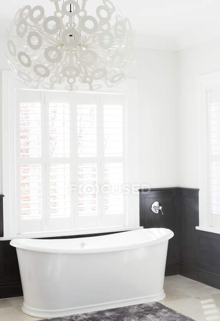 Banheira de imersão e lustre moderno em banheiro de luxo — Fotografia de Stock
