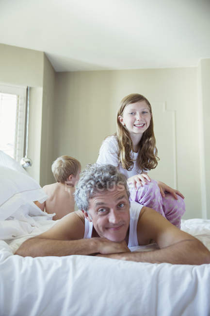 Батько грає з дітьми на ліжку — стокове фото
