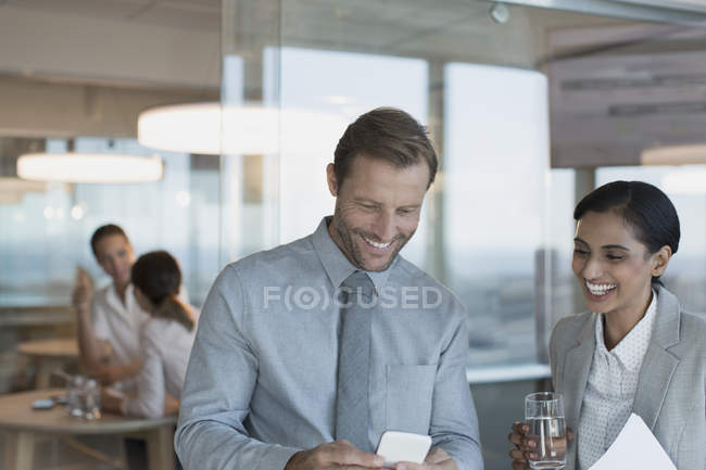 Homme d'affaires et femme d'affaires utilisant un téléphone portable au bureau — Photo de stock