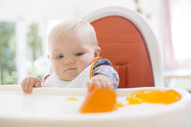 Baby girl eating in high chair — Stock Photo