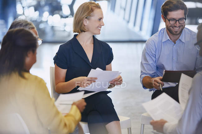 Empresários sorridentes discutindo papelada em reunião — Fotografia de Stock