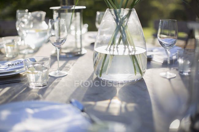 Vase and place settings on sunny patio table — Stock Photo