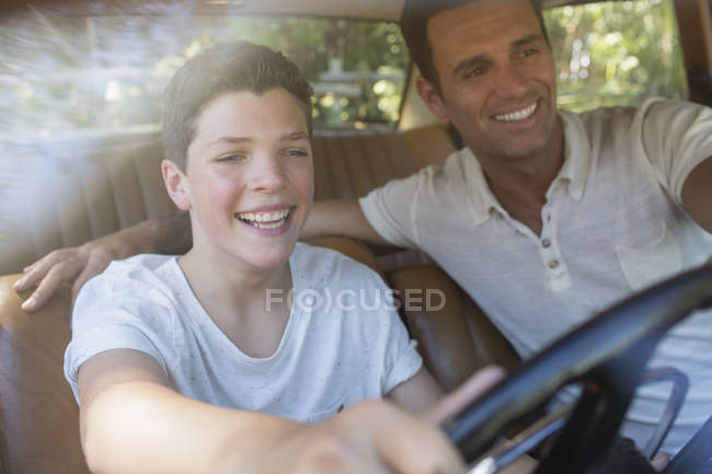 Feliz padre enseñando hijo a conducir coche - foto de stock