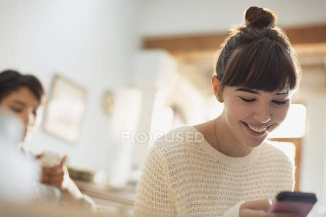 Sonriendo joven mujer mensajes de texto con el teléfono celular - foto de stock