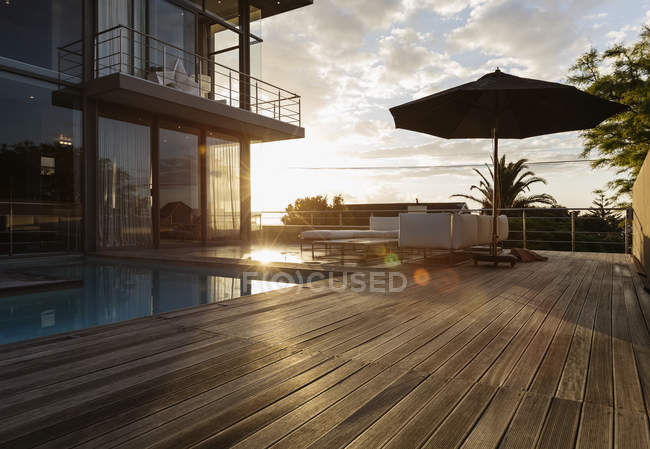 Sol atrás de casa de luxo com piscina — Fotografia de Stock