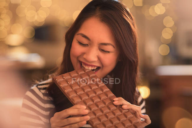 Mulher com desejo de dente doce mordendo em grande barra de chocolate — Fotografia de Stock
