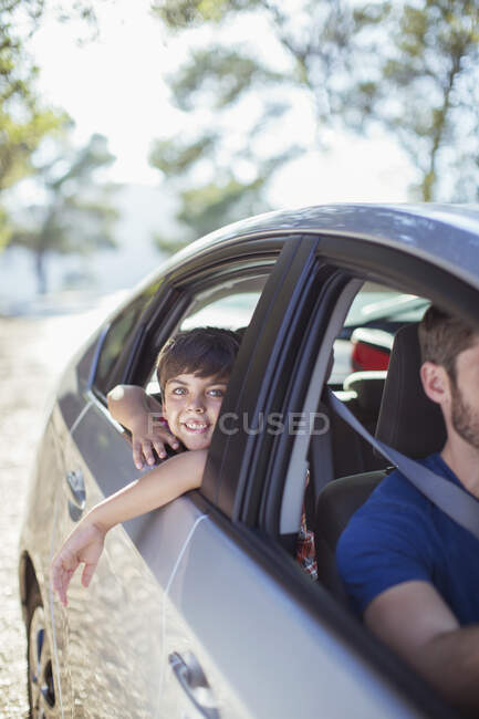 Portrait of smiling boy leaning out car window — Stock Photo