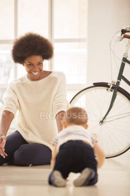 Mother watching baby boy crawl in living room at home — Stock Photo