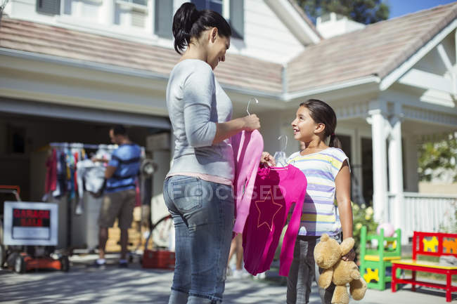 Madre e hija comprando ropa en la venta de jardín - foto de stock