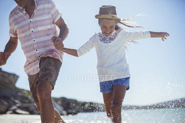 Familia corriendo en el agua en la playa - foto de stock