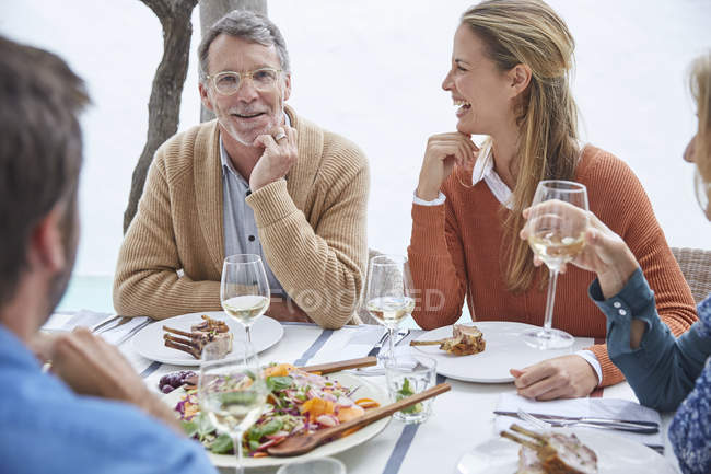 Paare trinken Weißwein und essen Mittagessen am Terrassentisch — Stockfoto